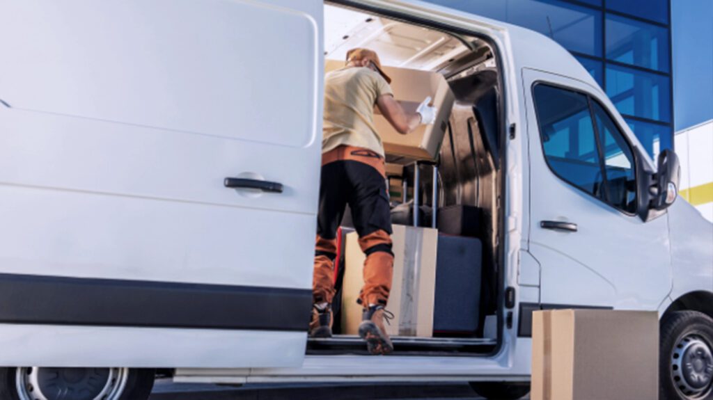 Delivery worker loading boxes into white van for same-day courier service