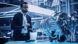 Engineer analyzing jet engine model on laptop in aerospace research facility